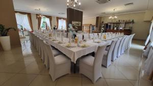 a long table with white tables and white chairs at Hotel Chańcza Spa & Restauracja in Raków