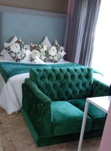 un sofá verde en una habitación con cama en Adante Lodge & Conferencing en Mthatha
