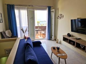 a living room with a blue couch and a tv at ARGO Downtown Apartment in Kalymnos