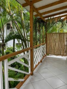 a wooden porch with a white fence and palm trees at El Mosquito Boutique Hotel Playa Bonita in Las Terrenas