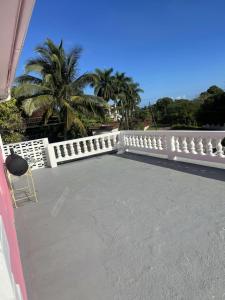 a white fence on a patio with palm trees at Three Palm Villa in Montego Bay