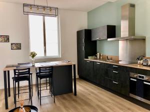 a kitchen with a table and some chairs in it at Maison Gabriel Appartement LUNE in Abbeville