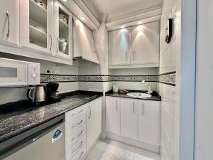 a white kitchen with white cabinets and a sink at Apartamentos Horizonte Estudio (8º-801) in Calpe