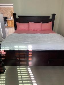 ein Schlafzimmer mit einem großen Bett mit rosa Kissen in der Unterkunft Three Palm Villa in Montego Bay