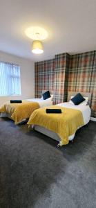 two beds in a hotel room with yellow blankets at 7 Guest 4 Bedrooms CITY CENTRE lovely home in Loughborough City Centre in Loughborough