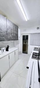 una cocina blanca con armarios blancos y fregadero en 7 Guest 4 Bedrooms CITY CENTRE lovely home in Loughborough City Centre, en Loughborough