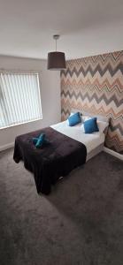 1 dormitorio con 1 cama grande con almohadas azules en 7 Guest 4 Bedrooms CITY CENTRE lovely home in Loughborough City Centre, en Loughborough