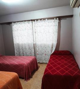 a room with two beds and a window with curtains at Departamento amplio a metros del mar in Puerto Madryn