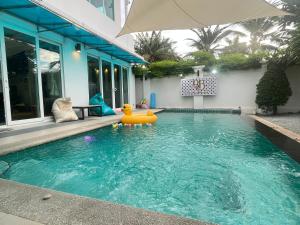 une piscine avec un parasol devant une maison dans l'établissement Cloud villa, à Pattaya (sud)