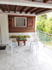 a porch with a couch and chairs and a tv at Villa de 3 chambres avec piscine privee jardin clos et wifi a Sainte Anne a 6 km de la plage in Sainte-Anne