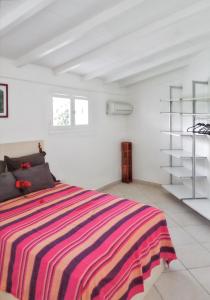 a white room with a bed with a colorful striped blanket at Villa de 3 chambres avec piscine privee jardin clos et wifi a Sainte Anne a 6 km de la plage in Sainte-Anne