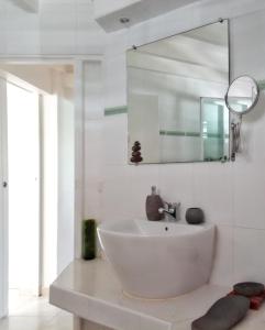 a white bathroom with a sink and a mirror at Villa de 3 chambres avec piscine privee jardin clos et wifi a Sainte Anne a 6 km de la plage in Sainte-Anne