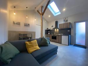 a living room with a blue couch and a kitchen at l'Atelier, sauna & spa in Riorges