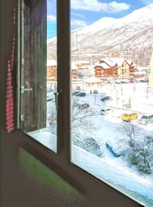 ein Fenster mit Blick auf einen schneebedeckten Hof in der Unterkunft Studio a Serre chevalier a 100 m des pistes avec jardin clos et wifi in La Salle Les Alpes
