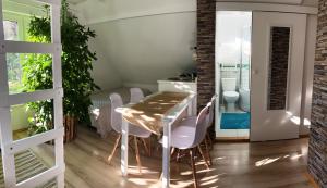 a dining room with a wooden table and white chairs at Apartament Pod Piórkiem in Krościenko