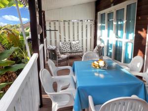 ブイヤントにあるBungalow de 2 chambres a Bouillante a 150 m de la plage avec terrasse amenagee et wifiのポーチ(青いテーブル、白い椅子付)