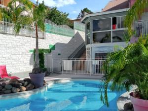 una piscina frente a una casa con palmeras en Appartement d'une chambre avec piscine partagee et wifi a Sainte Anne a 1 km de la plage, en Sainte-Anne