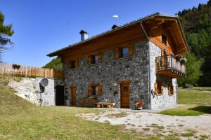 a stone house with a balcony on a hill at Chalet Ginepro - Chalet Maso Vecchio con vista montagne Passo Brocon, Trentino in Castello Tesino
