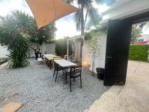 un patio avec tables, chaises et un parasol dans l'établissement Cloud villa, à Pattaya (sud)