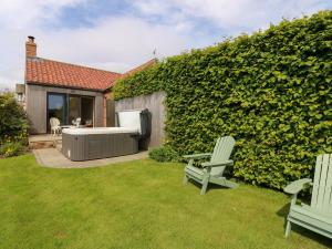 une cour avec deux chaises vertes et une haie verte dans l'établissement Lovesome Cottage, à Danby Wiske