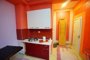 a kitchen with red and orange walls and a sink at Apartmani Lazić in Gracanica