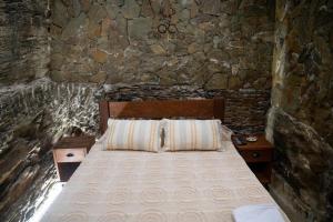 - une chambre avec un lit dans un mur en pierre dans l'établissement Quinta da Coitada - Alojamento Local, à Soutelo do Douro