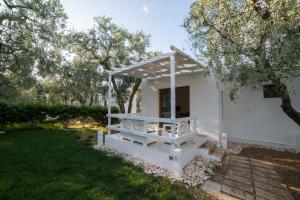 ein weißes Haus mit einer Veranda und Bäumen in der Unterkunft saracena Holiday Home with Private Beach and Swimming Pool in Mattinata