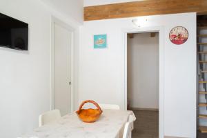a white dining room with a table with a basket on it at Meg Sicily House in Castellammare del Golfo