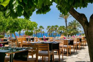 restauracja ze stołami i krzesłami z widokiem na ocean w tle w obiekcie Azia Resort & Spa w Pafos