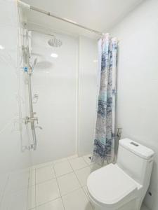 a white bathroom with a shower and a toilet at Urban Stays by Empress in Hulhumale +21 photos