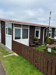 a house with a fence and a picnic table at Cozy Seaside Chalet in Bridlington in Bridlington