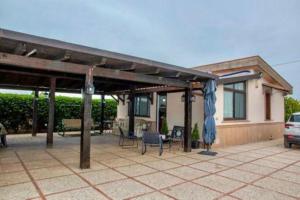 a patio with a roof with a table and a blue umbrella at casa Maruzza in Casteldaccia