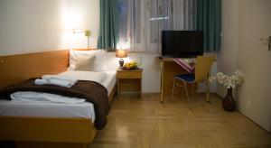 Habitación de hotel con cama, escritorio y TV. en Garni Hotel Rödelheimer Hof, en Frankfurt