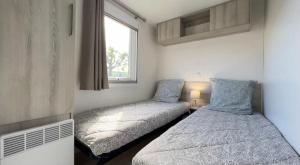 two beds in a small room with a window at CAMPING Siblu Le Montourey - LE FARNIENTE in Fréjus +11 photos