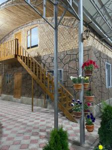 un edificio de piedra con una escalera y macetas en Amirhan Guest house, en Bokonbayevo
