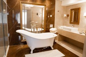 ein Bad mit einer Badewanne, einer Dusche und einem Waschbecken in der Unterkunft Hotel Daara in Gramado