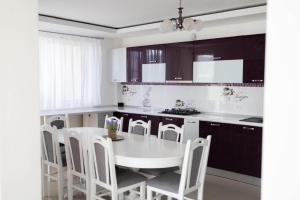 eine Küche mit einem weißen Tisch und weißen Stühlen in der Unterkunft Vila MEM in Sebeş + 12 Fotos