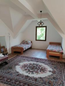 an attic room with two beds and a rug at Pelister Riverside Villa in Bitola