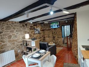 a living room with a table and a stone wall at A Casiña de Arretén in Padrón