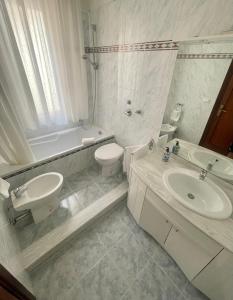 e bagno bianco con lavandino, servizi igienici e vasca. di Home Sisters a Trapani