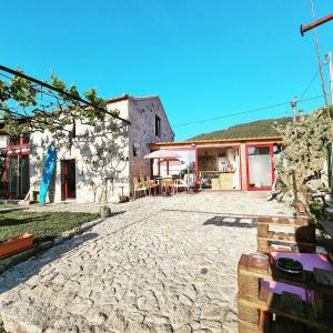 un patio de piedra con un edificio con mesa y sillas en Albergue Casa do Sardão, en Carreço