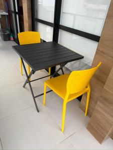 une table noire et deux chaises jaunes dans une pièce dans l'établissement House Barra 603 · Novíssimo apt Vista Mar na Barra, à Salvador