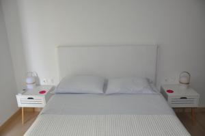 ein weißes Schlafzimmer mit zwei weißen Tischen und einem Bett in der Unterkunft Athens Sea Front Apartment - Athenian Riviera in Varkiza