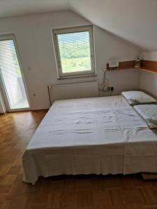 Una cama blanca grande en una habitación con dos ventanas. en Brod on the Hill, en Bohinj