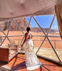 Una mujer con un vestido blanco mirando hacia el desierto en RUM SUNRlSE LUXURY CAMP en Wadi Rum