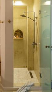 um chuveiro com uma porta de vidro na casa de banho em Manus Dei Exclusive Suites em Pythagoreio