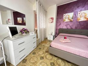 una camera da letto con un letto rosa e un computer su una cassettiera di Appartamento Donna Carmela a Tropea