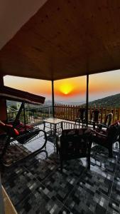 un balcón con sillas, mesas y una puesta de sol en Mustafa Farm, en Ajloun