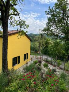 a yellow house with flowers in a garden at Luci nel Bosco 