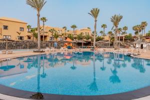 a large pool at a resort with chairs and palm trees at Casa Emma in Corralejo